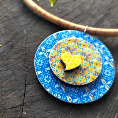 Colar com pendentes circulares pintados em azul, amarelo e branco, com um coração pequeno