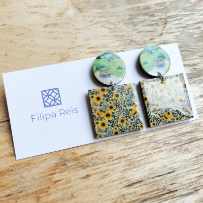 Brincos com padrões florais e cartão Filipa Reis sobre madeira clara