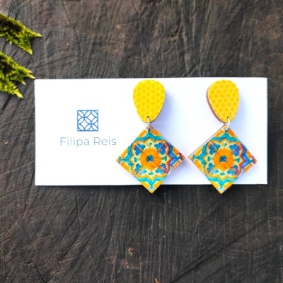 Brincos coloridos em cartão de marca sobre madeira escura