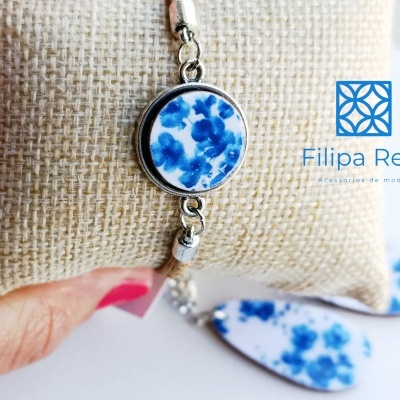 Pulseira com pingente redondo azul e branco sobre almofada bege