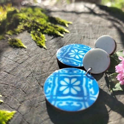 Brincos azuis e cinzentos com padrão floral sobre tronco de árvore