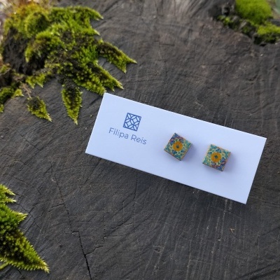 Brincos quadrados com padrão floral em cartolina com logotipo 'Filipa Reis' sobre madeira