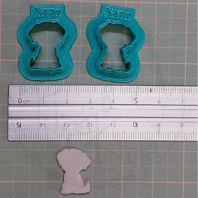 Dois cortadores de biscoitos azuis em forma de cachorro com texto Kane e régua metálica.