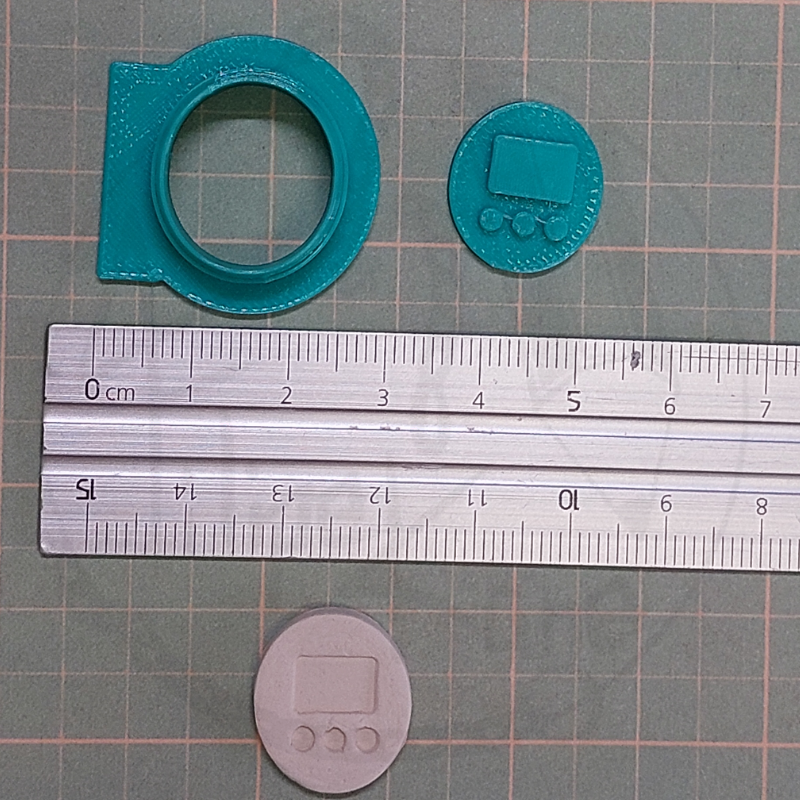 Objetos circulares azuis e branco sobre superfície quadriculada verde com réguas de metal