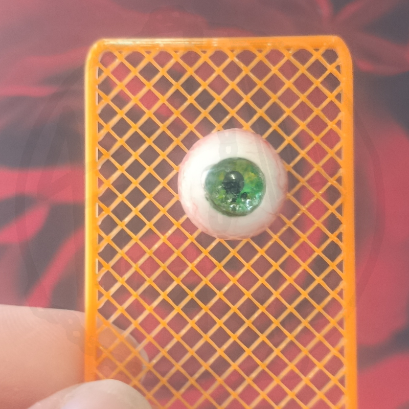 Suporte laranja com bola de olho artificial verde e branca