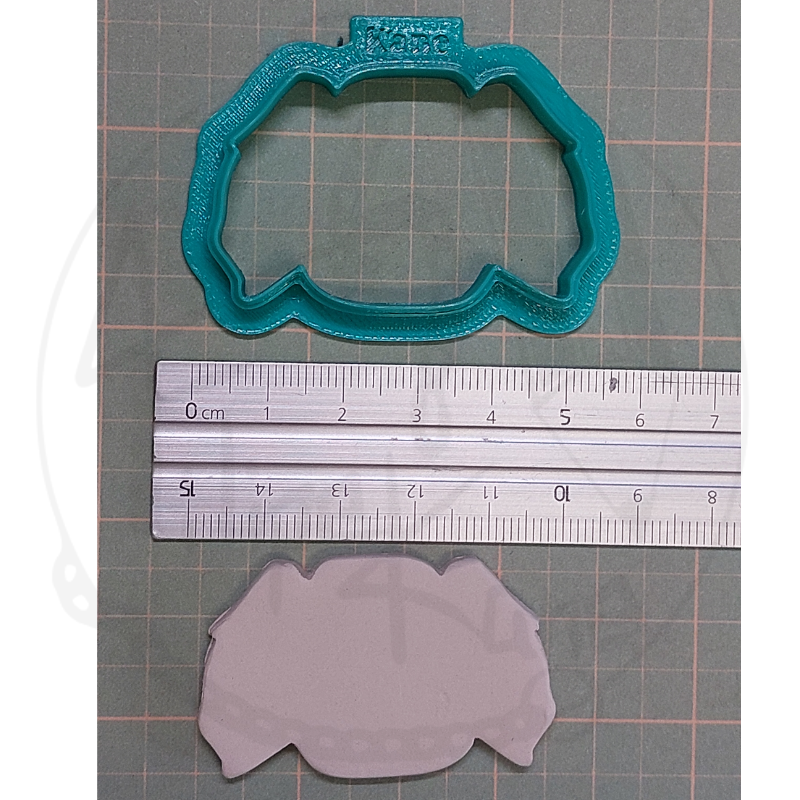 Cortador de bolachas verde, régua metálica e massa moldada no fundo quadriculado