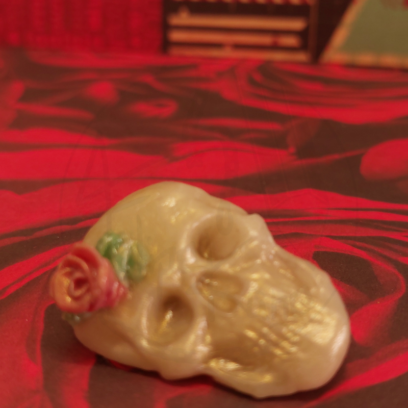 Escultura de caveira com flor sobre fundo vermelho com rosas