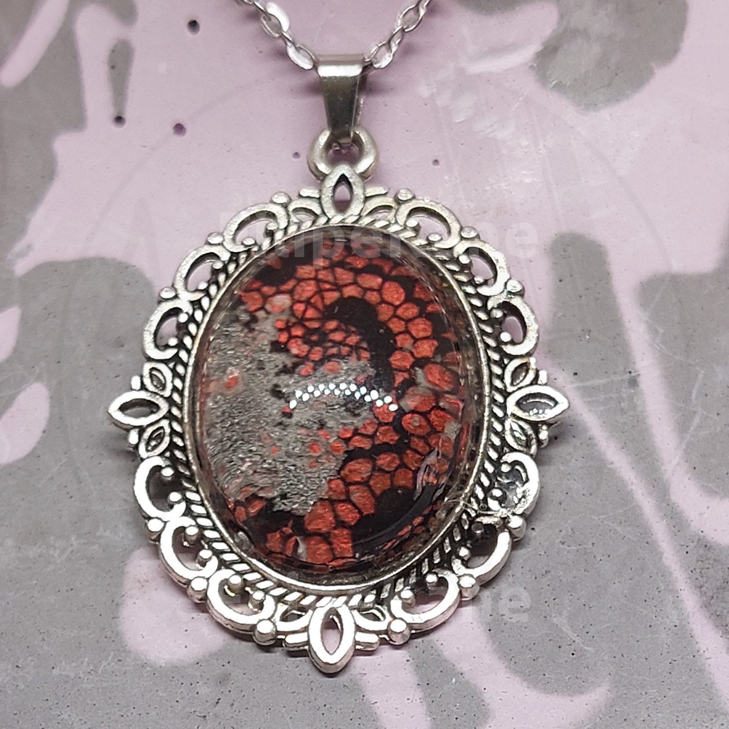 Colar com pendente oval de metal prateado e pedra com padrão abstracto vermelho e preto