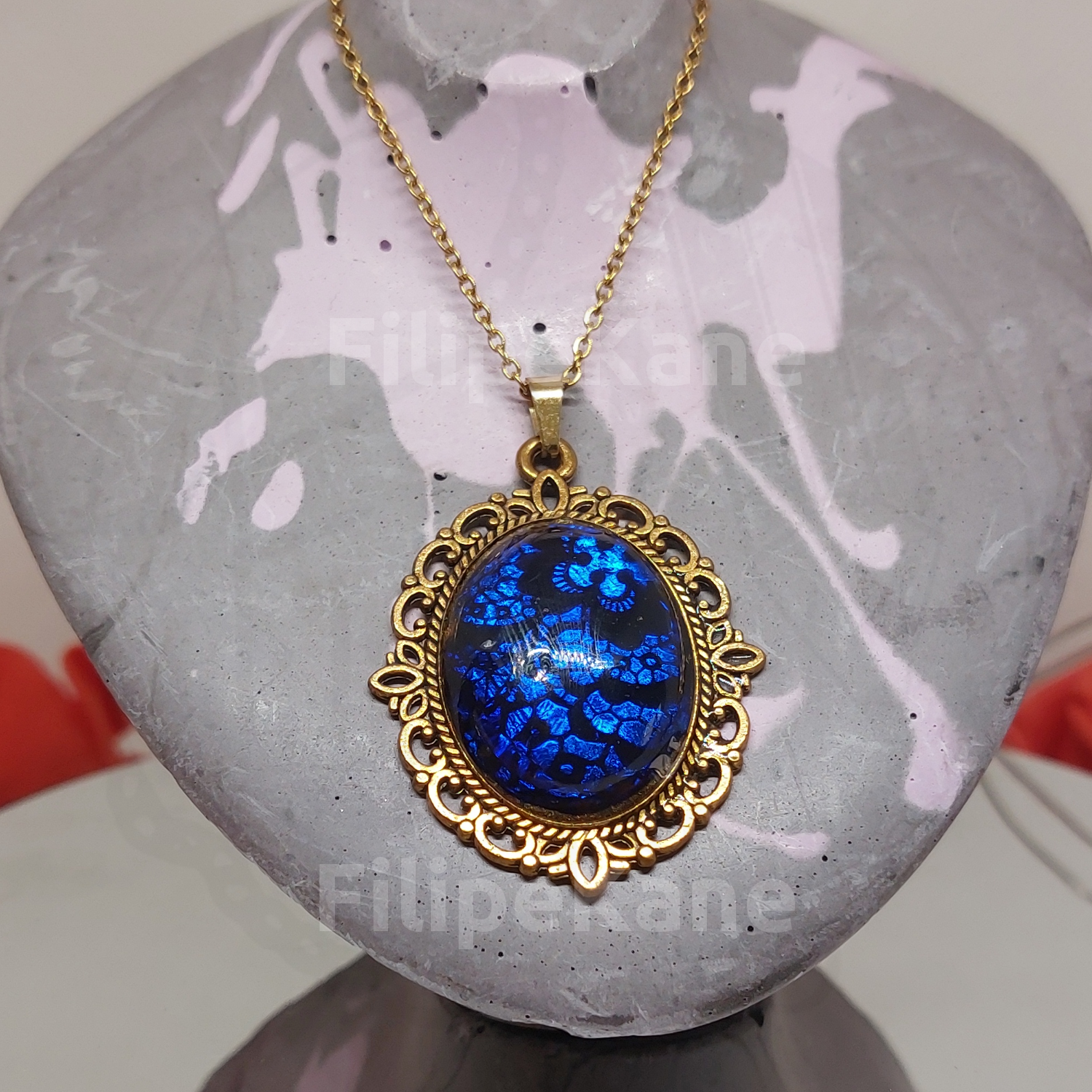 Colar com pendente azul oval e corrente dourada em busto cinzento