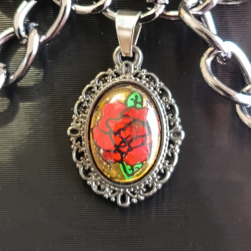 Colar com corrente prateada e pendente oval com desenho de rosa vermelha e fundo dourado