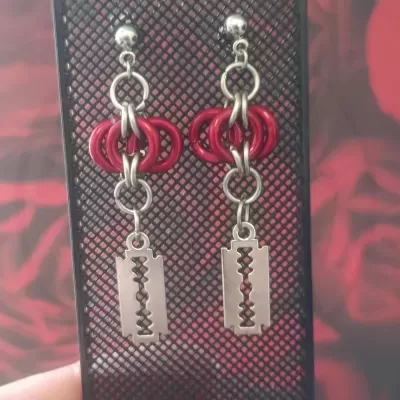 Brincos pendentes com argolas vermelhas e lâminas prateadas em suporte preto