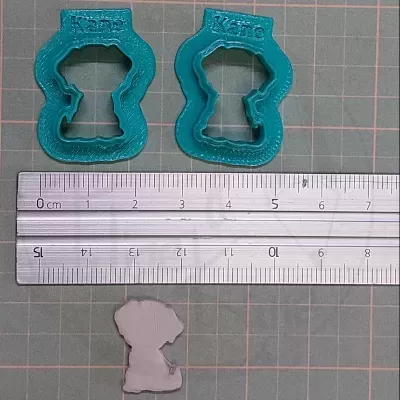 Dois cortadores de biscoitos azuis em forma de cachorro com texto Kane e régua metálica.