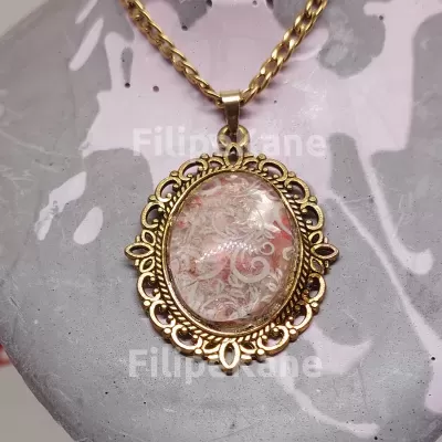 Colar com pendente oval dourado com padrão decorativo