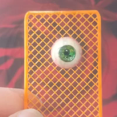 Suporte laranja com bola de olho artificial verde e branca