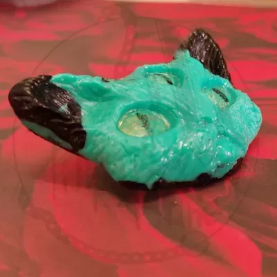 Peça decorativa azul turquesa e preta com cavidades circulares sobre fundo vermelho