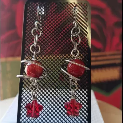 Brincos pendentes com esfera vermelha e estrela vermelha translúcida em suporte preto
