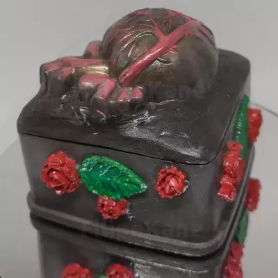 Caixa decorativa castanho escuro com rosas vermelhas, folhas verdes e crânio em relevo