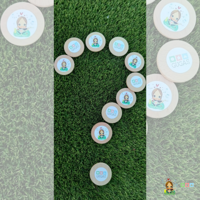 Caixas redondas de madeira com etiquetas coloridas dispostas em forma de interrogação na relva