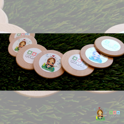 Discos de madeira com imagens e texto GUGAS sobre relva artificial