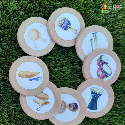 Oito círculos de madeira com imagens de instrumentos musicais, dispostos em círculo sobre relvado.