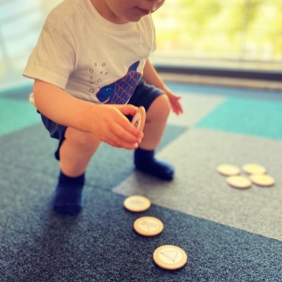 Criança a jogar com discos de madeira num tapete colorido interior