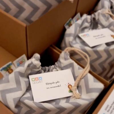 Sacolas de tecido cinza e branco em caixas de cartão com etiquetas de agradecimento