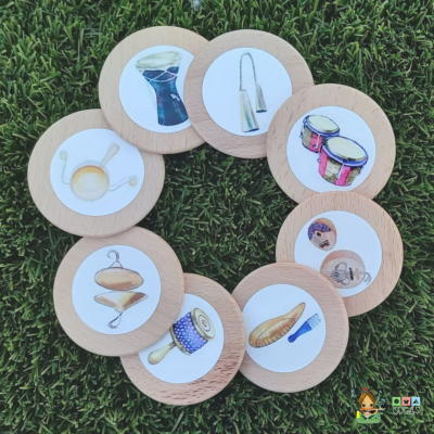 Peças de madeira com desenhos de instrumentos musicais tradicionais sobre relva