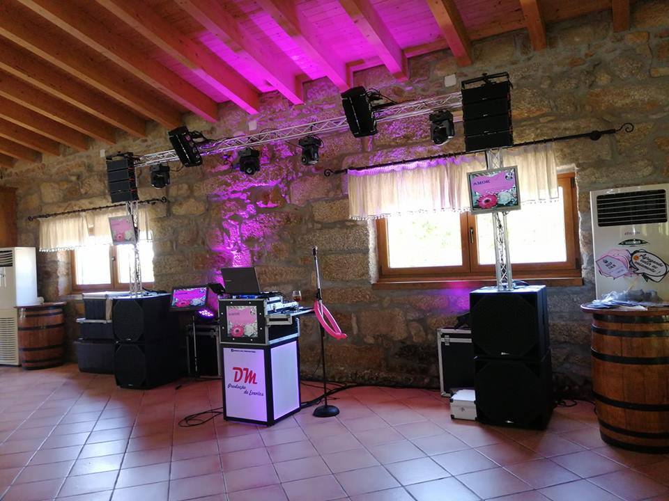 Sistema de som e luzes com equipamento de DJ e microfone em espaço rústico com teto de madeira e paredes de pedra.