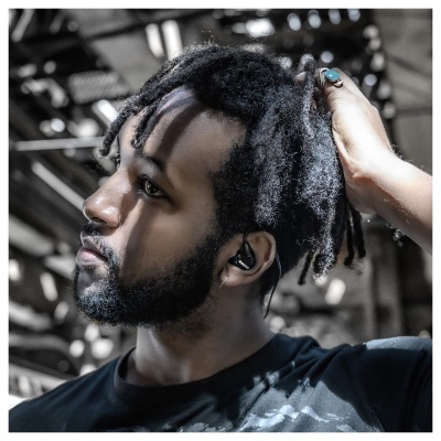 Homem com auriculares negros sem fios numa ambiente industrial