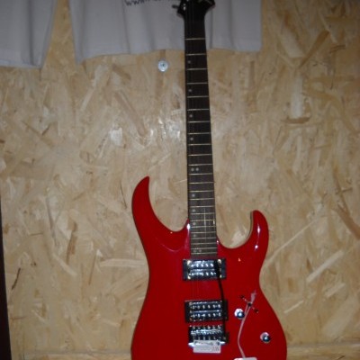 Guitarra elétrica vermelha pendurada numa parede de madeira aglomerada