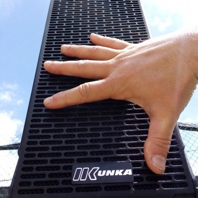 Coluna de som preta com mão pousada e etiqueta KUNKA