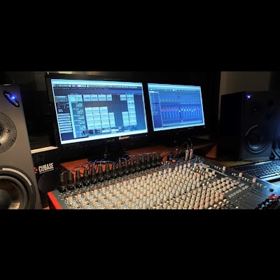 Mesa de mistura de áudio com monitores e colunas em estúdio escuro