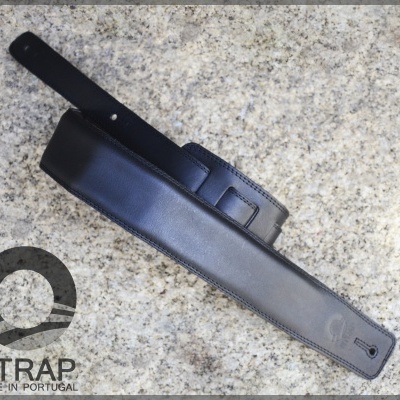 Correia de guitarra em pele preta com fivela preta sobre fundo cinzento granilhado