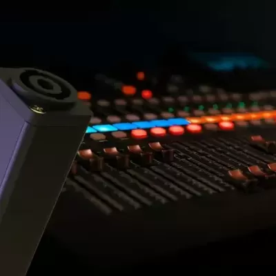 Microfone Audix i5 preto com mesa de mistura iluminada em fundo escuro