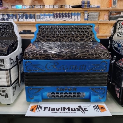 Três acordeões decorativos com botões e detalhes metálicos em várias cores numa loja de música