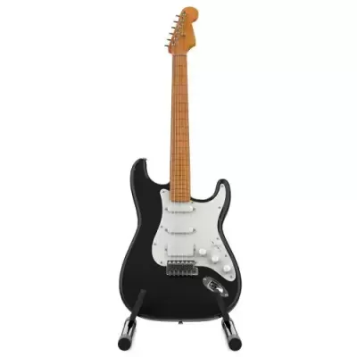 Guitarra elétrica preta com braço de madeira clara em pé em suporte preto