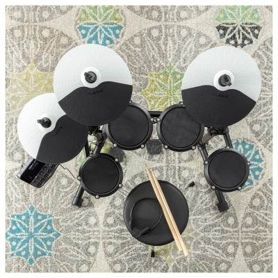 Bateria eletrónica preta e branca com baquetas sobre tapete colorido