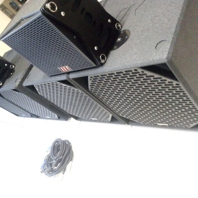 Conjunto de colunas de som preto com fios ao lado no chão