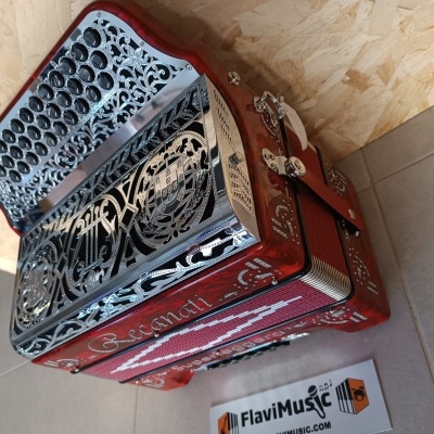 Acordeão vermelho com botão preto e detalhes metálicos prateados com padrão artístico