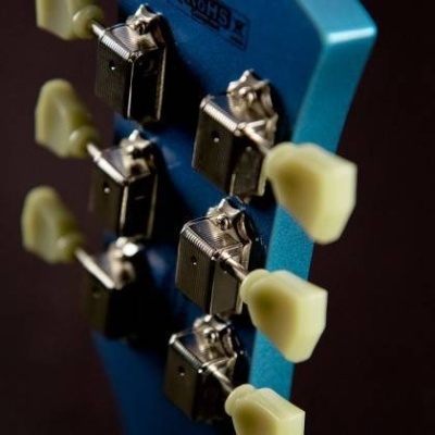 Cabeça de guitarra azul com cravelhas metálicas e botões de afinamento creme