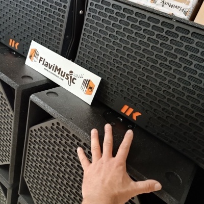 Altifalantes pretos com cartão FlaviMusic e mão tocando um altifalante