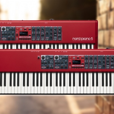 Dois teclados digitais Nord Piano 5 vermelhos com teclas brancas e pretas junto a uma parede de tijolos.