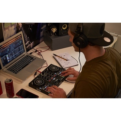 Pessoa a usar mesa de mistura DJ e computador portátil num ambiente interno