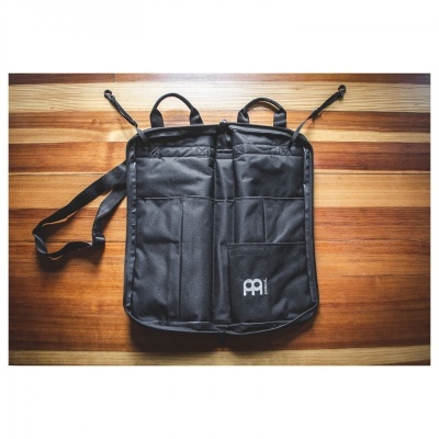 Mochila preta com vários bolsos e logotipo PAI sobre mesa de madeira