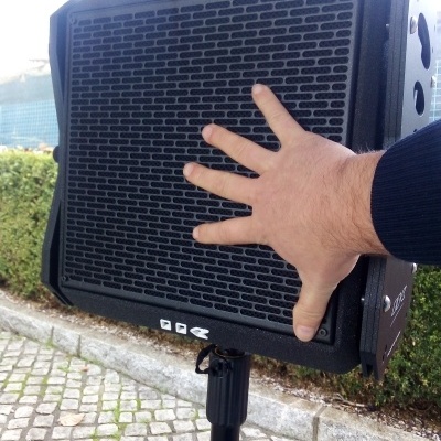 Coluna de som preta em tripé ao ar livre com mão pousada na grade frontal