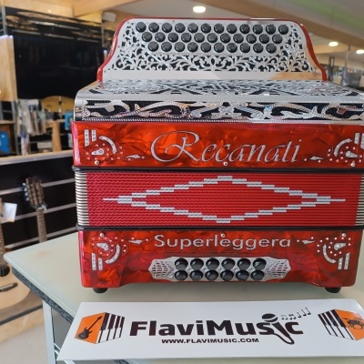 Acordeão vermelho Recanati Superleggera sobre mesa com cartão FlaviMusic e guitarras ao fundo