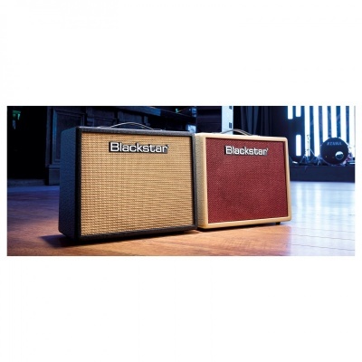 Dois amplificadores de guitarra Blackstar com grelhas de tecido, um preto com bege e outro bege com vermelho, em palco de madeira.