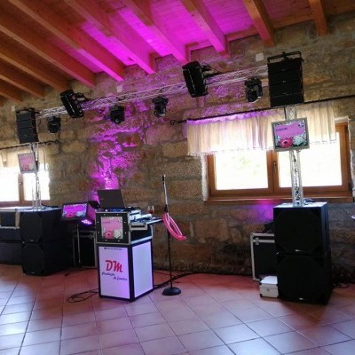 Sistema de som e luzes com equipamento de DJ e microfone em espaço rústico com teto de madeira e paredes de pedra.