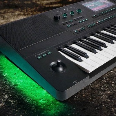 Teclado musical preto com iluminação verde sob ele, em chão escuro