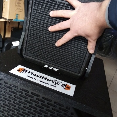 Colunas de som pretas com mão segurando uma e autocolante FlaviMusic